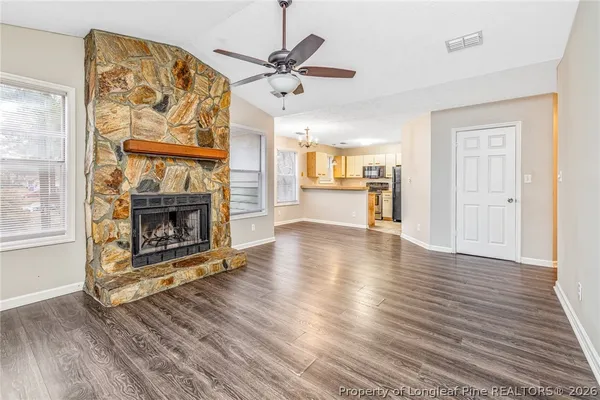 an empty room with wooden floor a fireplace and a window