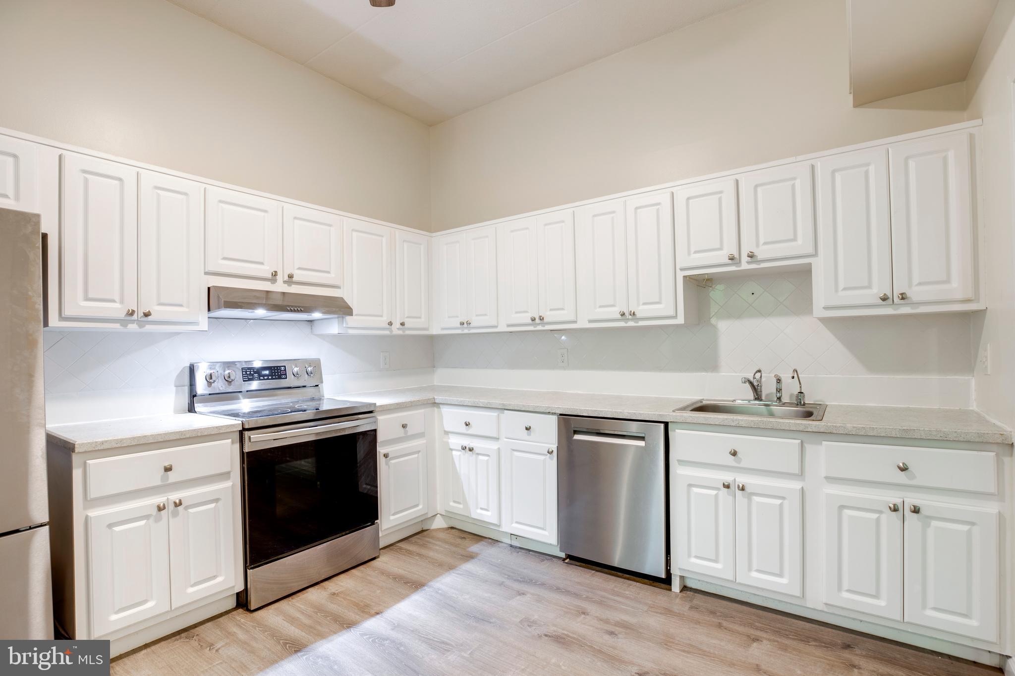 2106 Green Watch Way, Unit 101 Reston, VA 20191 - Photo 16 of 40 a kitchen with white cabinets sink and stainless steel appliances