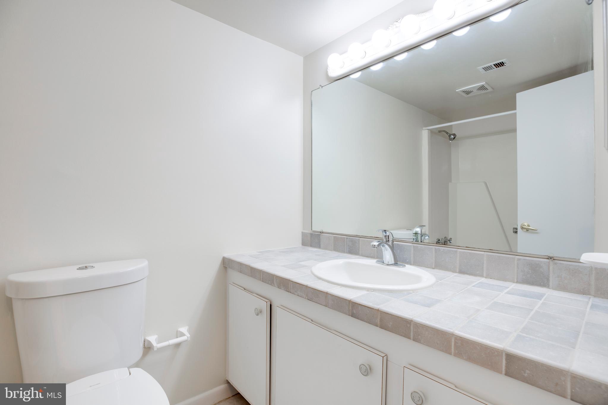 2106 Green Watch Way, Unit 101 Reston, VA 20191 - Photo 31 of 40 a bathroom with a granite countertop sink a toilet and a mirror