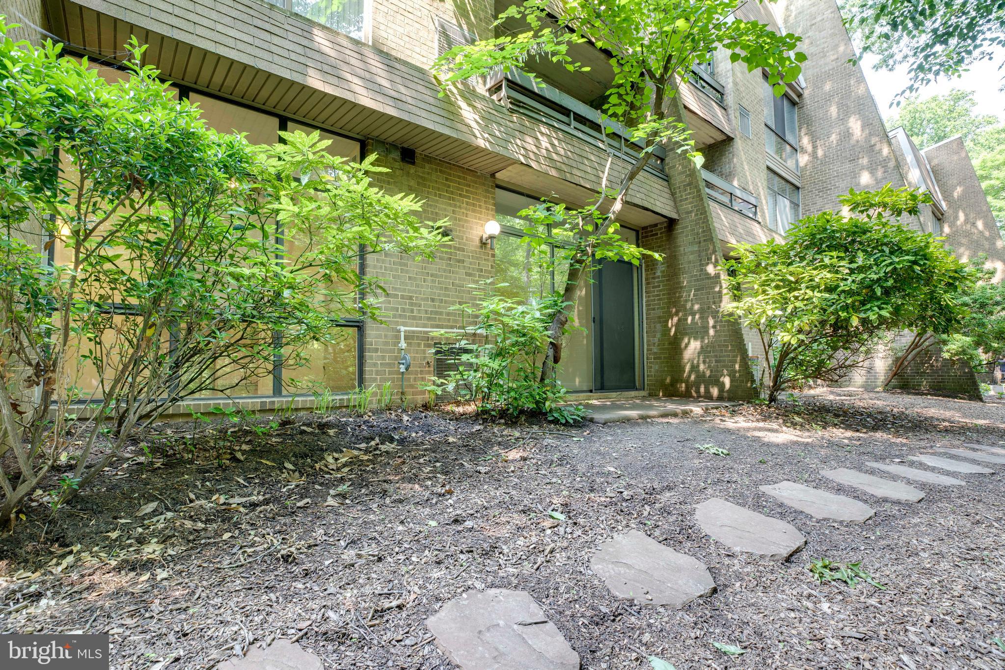 2106 Green Watch Way, Unit 101 Reston, VA 20191 - Photo 35 of 40 a backyard of a house with large trees and plants