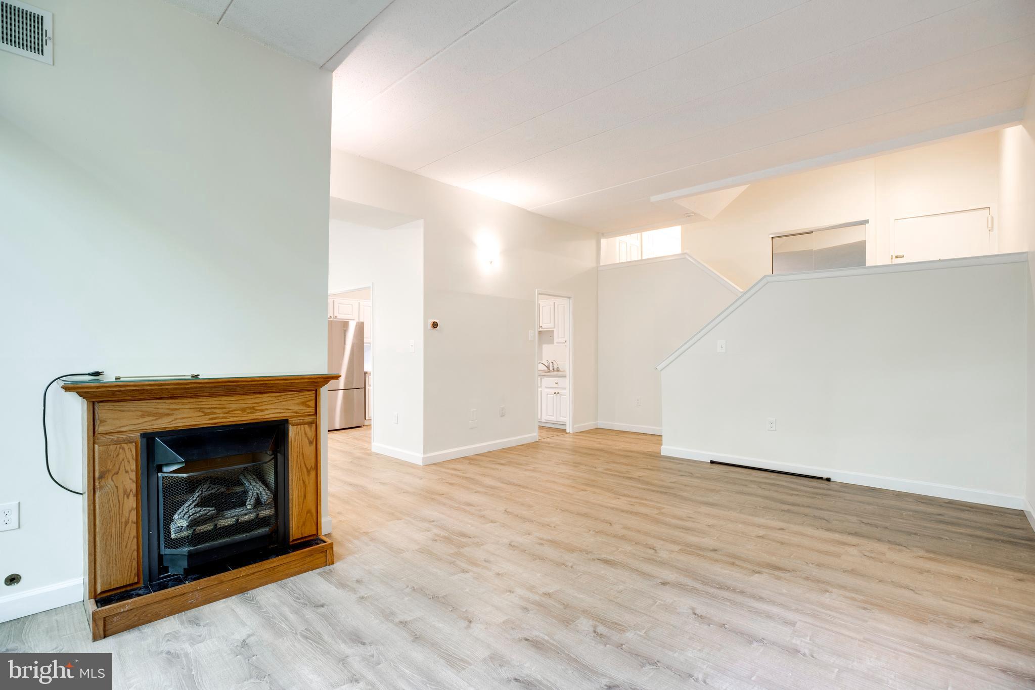 2106 Green Watch Way, Unit 101 Reston, VA 20191 - Photo 9 of 40 a view of an empty room with wooden floor fireplace and a window