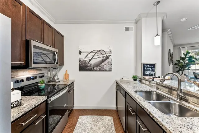 a kitchen that has a sink wooden cabinets and stainless steel appliances