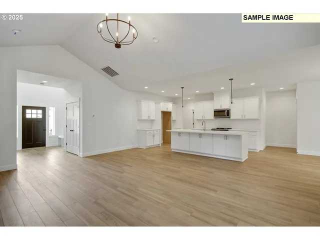 a view of kitchen and empty room with wooden floor