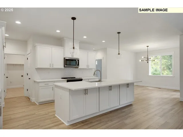 a kitchen with stainless steel appliances granite countertop a refrigerator a sink dishwasher a stove and white countertops with wooden floor