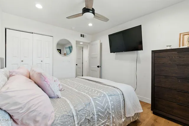 a bedroom with a bed a mirror and a flat tv screen on dresser