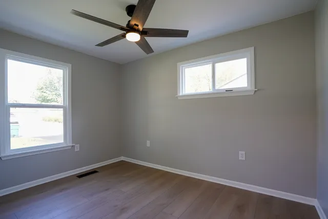 an empty room with a window and a fan