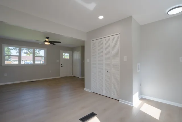 an empty room with wooden floor cabinet and windows
