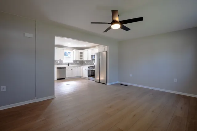 an empty room with windows and ceiling fan