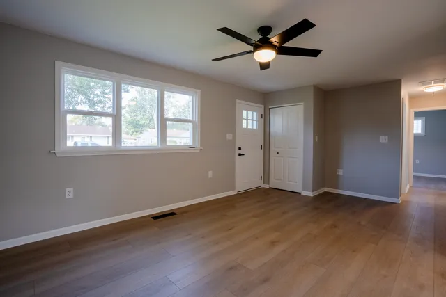 an empty room with wooden floor and windows