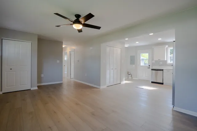 a view of an empty room with wooden floor and a ceiling fan