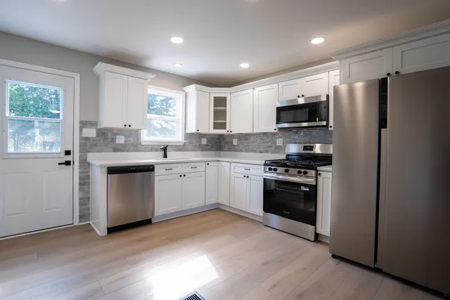 a kitchen with stainless steel appliances a sink a stove a refrigerator cabinets and a window