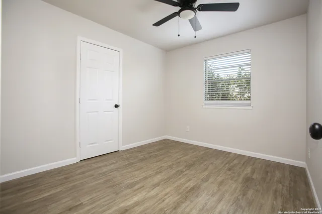 an empty room with a window and a ceiling fan