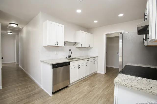 a kitchen with granite countertop a sink stove and refrigerator