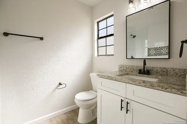 a bathroom with a granite countertop sink mirror vanity and toilet
