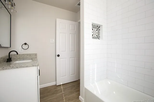 a bathroom with a granite countertop sink a mirror and a bathtub