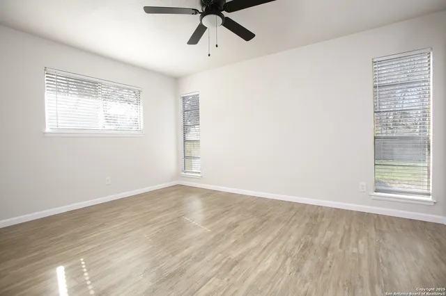 a view of an empty room with a window and wooden floor