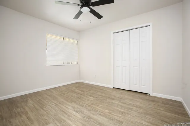 an empty room with wooden floor closet and windows