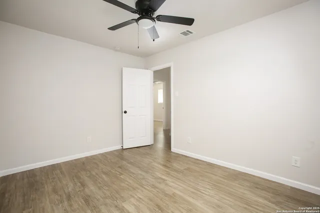 an empty room with a ceiling fan and wooden floor