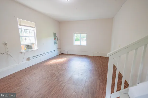 an empty room with wooden floor and windows