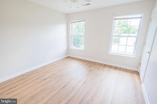 an empty room with wooden floor and windows