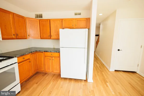 a view of a kitchen with wooden floor and a refrigerator
