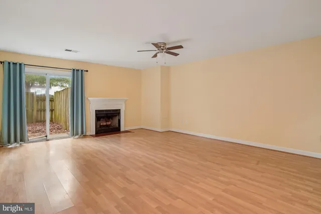 an empty room with fireplace fan and windows