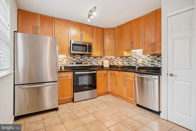 a kitchen with stainless steel appliances granite countertop a refrigerator sink and stove