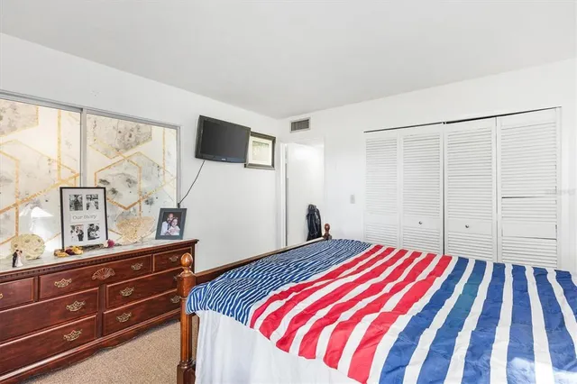 a bedroom with a bed and a flat tv screen on dresser