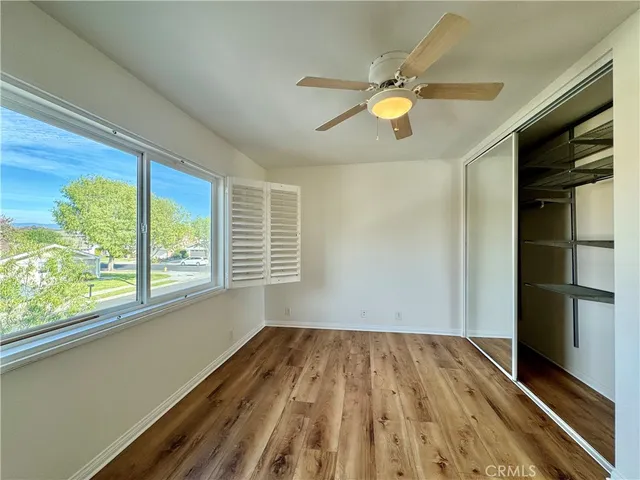 a view of empty room with wooden floor and fan