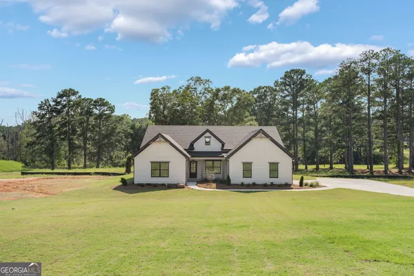 a view of a white house with a big yard and large trees