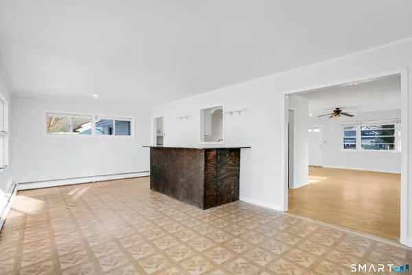 a view of an empty room with kitchen and window