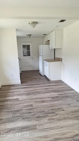a view of a room with wooden floors and white walls