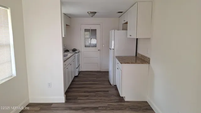 a hallway with white cabinets and wooden floor