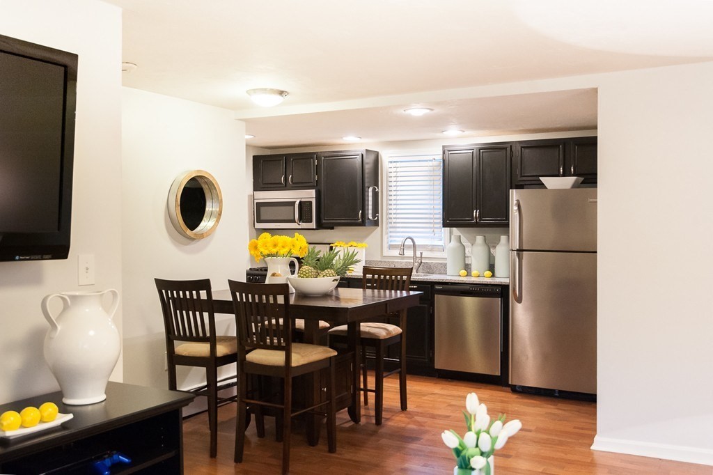 224 West Sixth Street, Unit 2 Boston, MA 02127 - Photo 7 of 18 a kitchen with stainless steel appliances granite countertop a dining table chairs refrigerator and sink