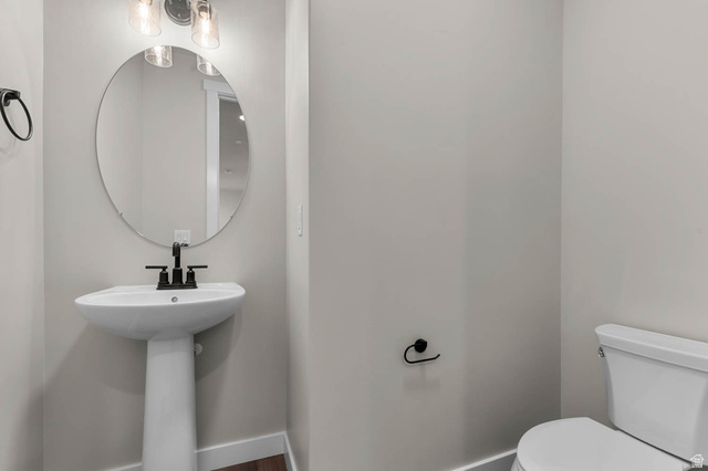1567 North 3250 West Provo, UT 84601 - Photo 7 of 22 Pedestal sink with matte black faucet, oval wall mirror, and three-light vanity fixture