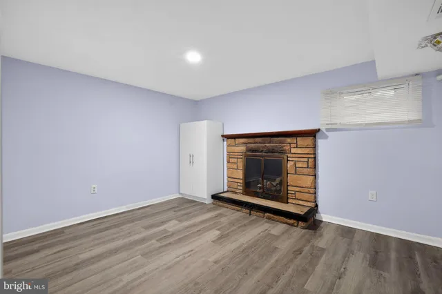 a view of an empty room with wooden floor and a fireplace