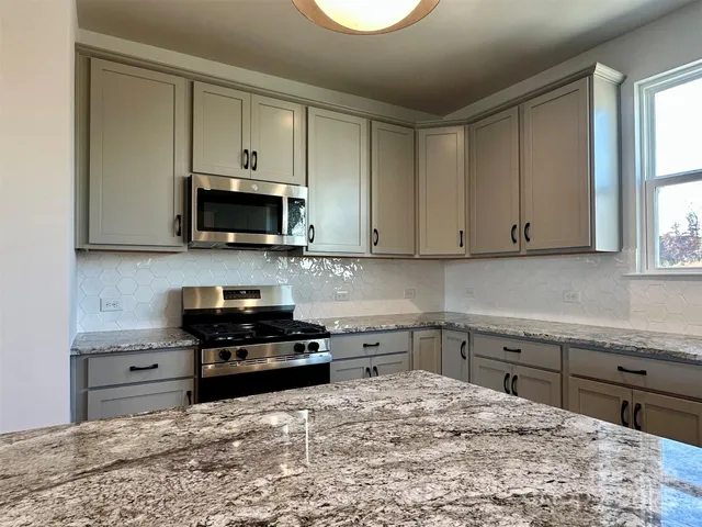 a kitchen with stainless steel appliances granite countertop a stove a sink and a microwave