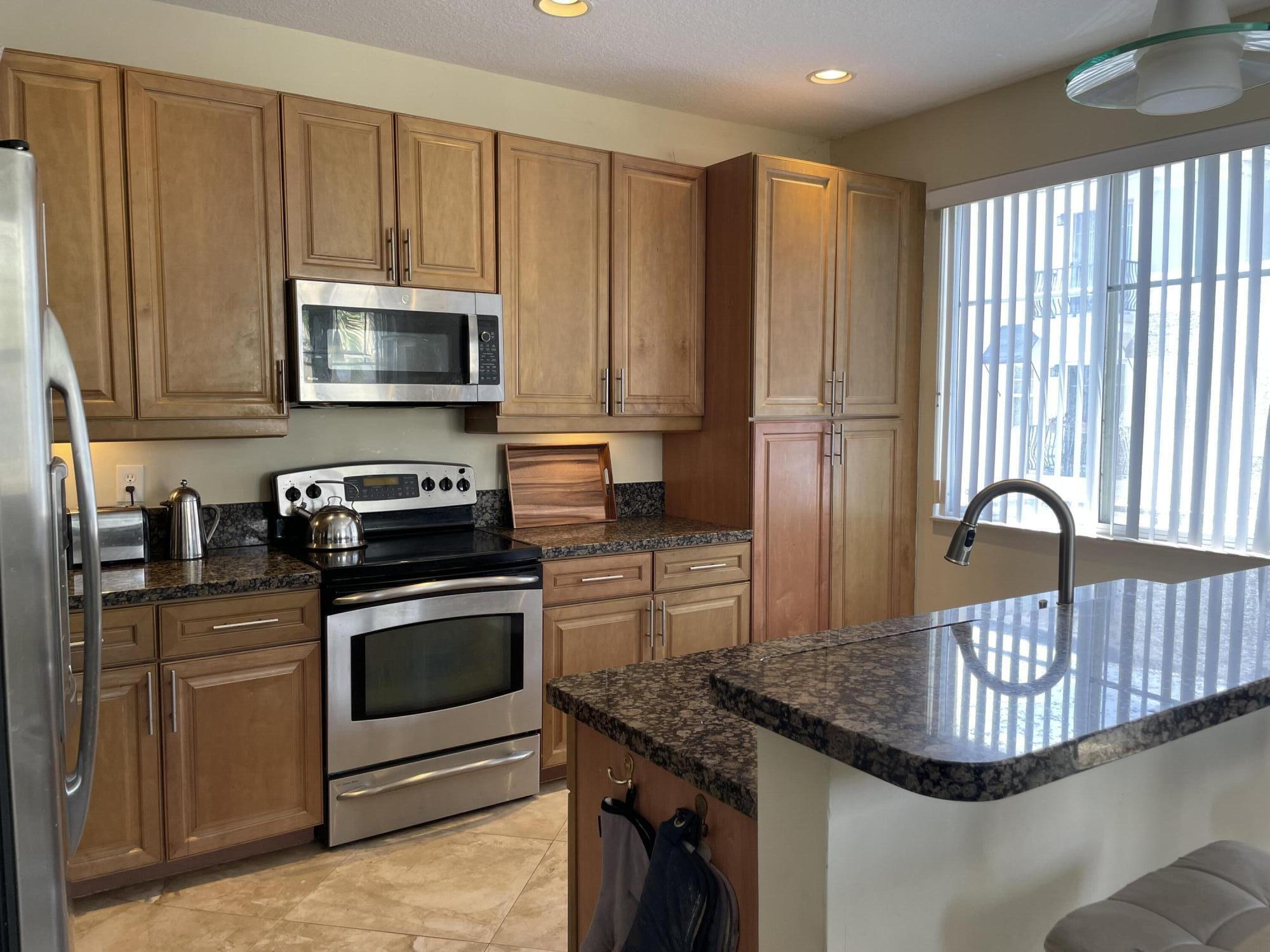 552 North West 39th Circle Boca Raton, FL 33431 - Photo 4 of 33 a kitchen with kitchen island granite countertop a stove top oven a sink and cabinets