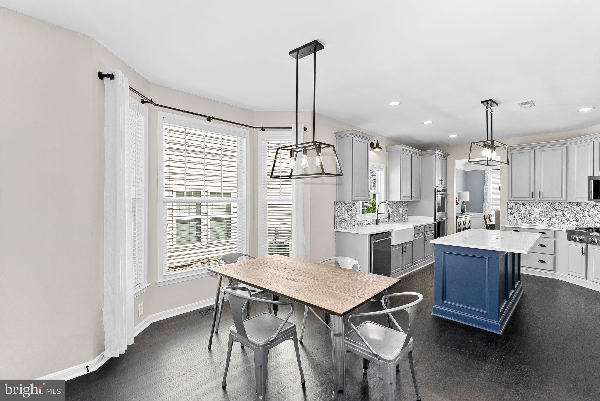 23388 Minerva Drive Brambleton, VA 20148 - Photo 18 of 57 a kitchen with kitchen island a dining table chairs stainless steel appliances and cabinets