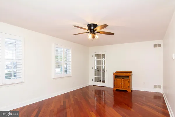 an empty room with windows and chandelier fan