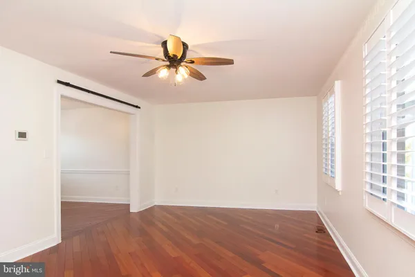 a view of empty room with wooden floor and fan