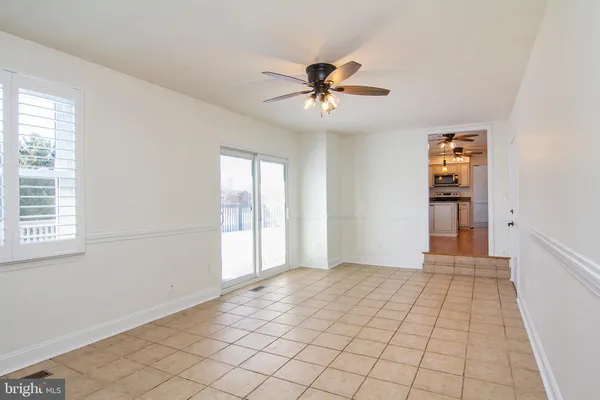 a view of an empty room with window and chandelier fan