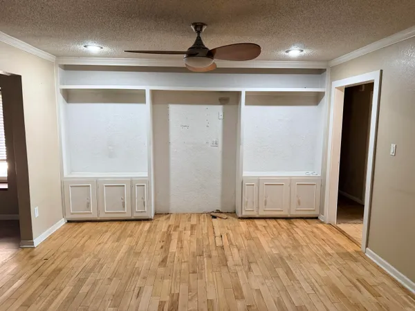 a view of empty room with wooden floor and fan