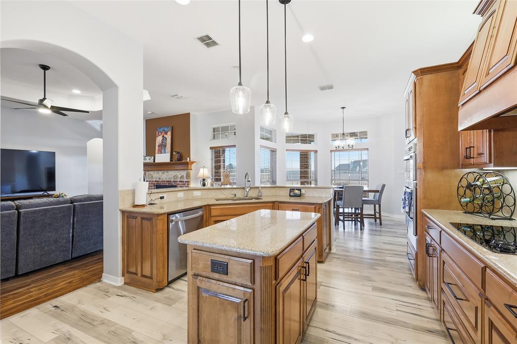 7915 Stone Ridge Drive Northlake, TX 76247 - Photo 13 of 40 a kitchen with stainless steel appliances granite countertop a stove top oven a sink dishwasher a dining table and chairs with wooden floor