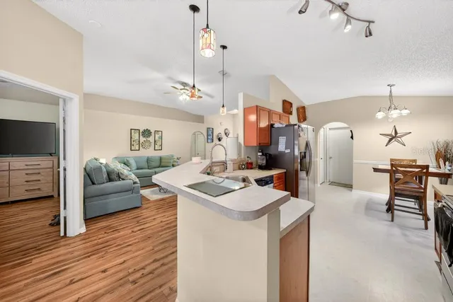 a view of a kitchen with kitchen island stainless steel appliances a stove a sink and living room view