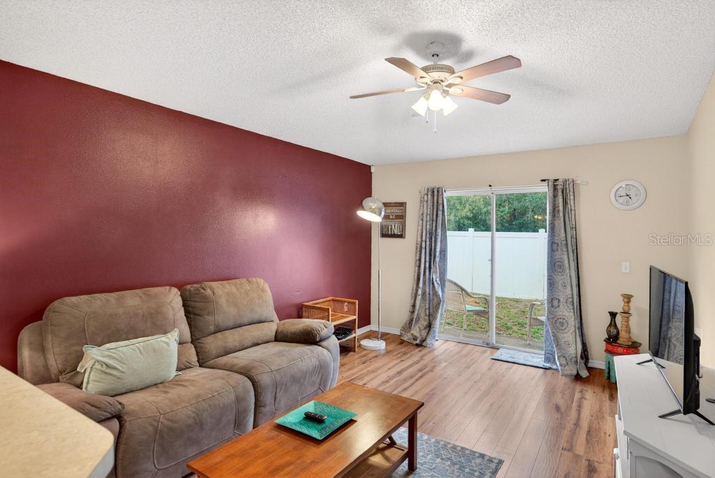 1332 Honey Road Apopka, FL 32712 - Photo 25 of 59 a living room with furniture a flat screen tv and a floor to ceiling window