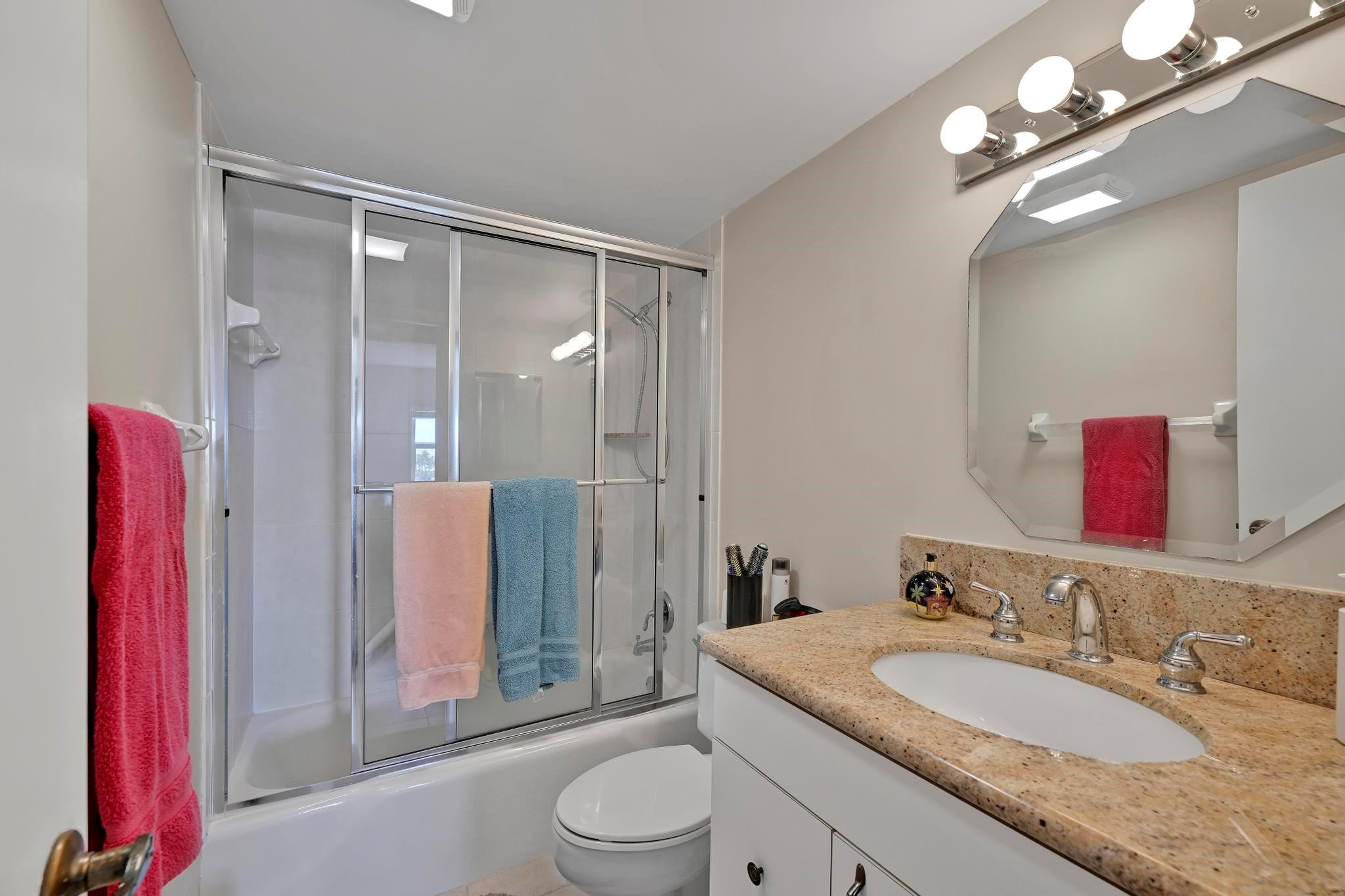 400 North Riverside Drive, Unit 404 Pompano Beach, FL 33062 - Photo 13 of 29 a bathroom with a granite countertop sink a toilet a mirror and shower