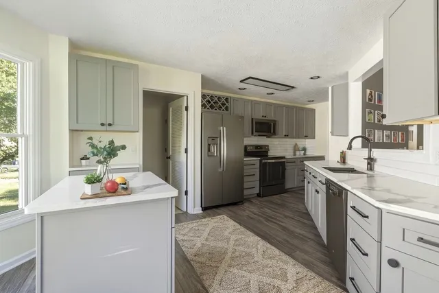 a kitchen with stainless steel appliances kitchen island granite countertop a refrigerator sink and white cabinets