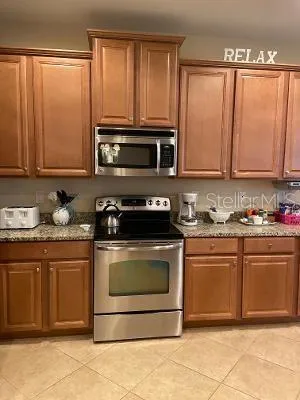 a kitchen with granite countertop a stove top oven microwave and cabinets