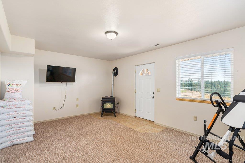 1028 Granlund Road Troy, ID 83871 - Photo 39 of 46 Pellet stove with visible flue pipe, white interior door with arched glass panels, and a window with blinds